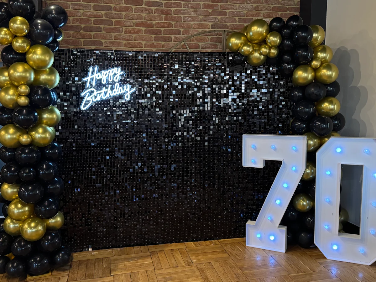 Czarno-złota ścianka zdjęciowa z cyframi LED 70 i napisem Happy Birthday